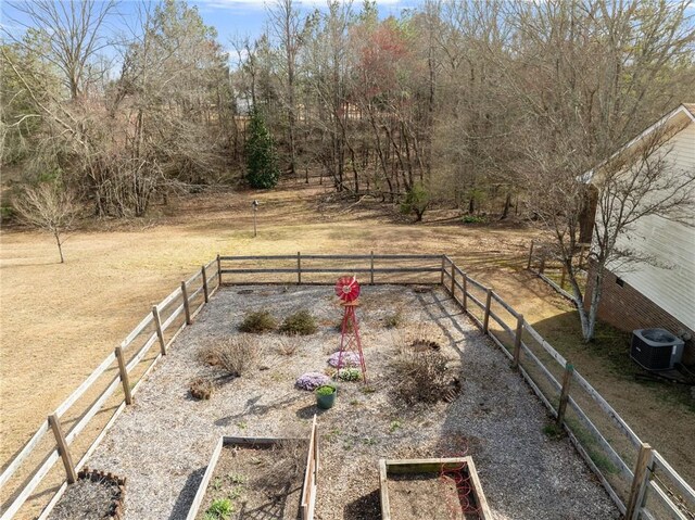 view of yard with a rural view, a vegetable garden, fence, and central AC