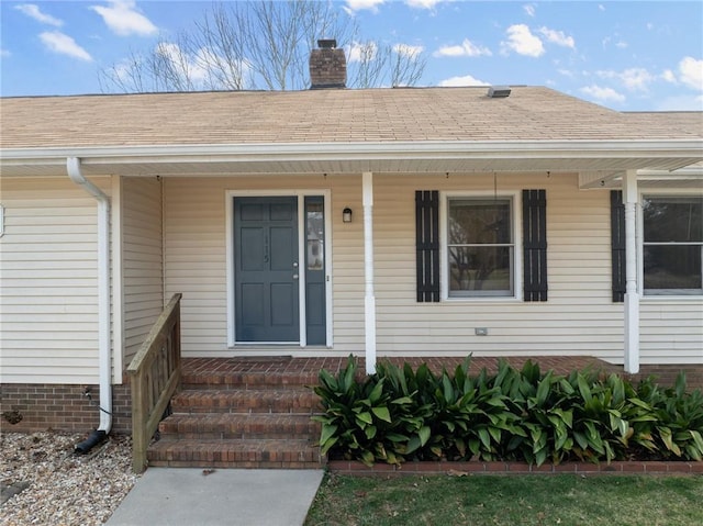 property entrance with roof with shingles, covered porch, and a chimney