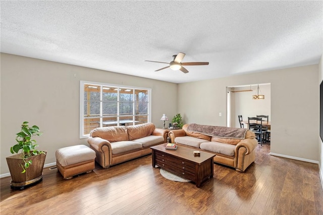 living room featuring a textured ceiling, baseboards, wood-type flooring, and ceiling fan