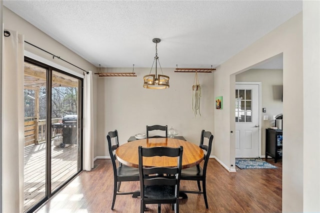 dining room featuring baseboards, a textured ceiling, and wood finished floors