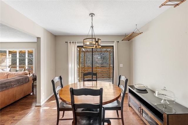 dining space featuring baseboards, a textured ceiling, and light wood finished floors