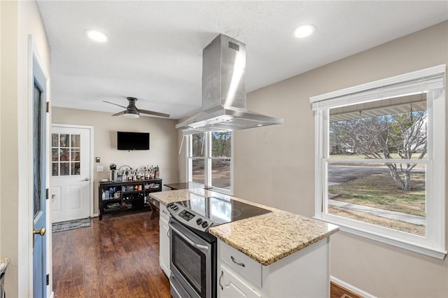 kitchen with dark wood finished floors, stainless steel range with electric stovetop, a healthy amount of sunlight, and island range hood