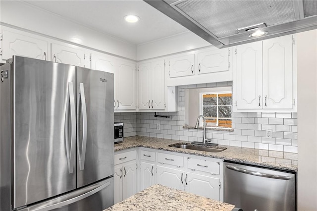 kitchen with light stone countertops, a sink, decorative backsplash, stainless steel appliances, and white cabinets