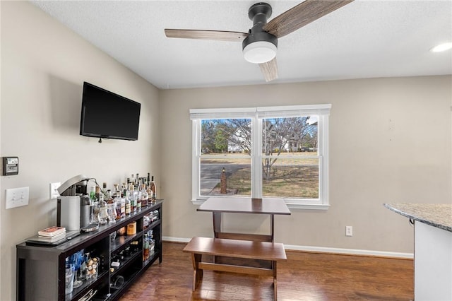 dining room with baseboards, a dry bar, a textured ceiling, a ceiling fan, and dark wood-style flooring