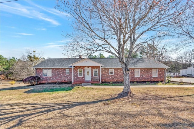 ranch-style home featuring a front lawn, brick siding, and a chimney