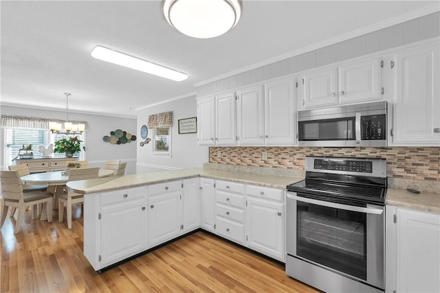 kitchen featuring crown molding, decorative backsplash, appliances with stainless steel finishes, a peninsula, and white cabinets