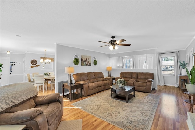 living room featuring ceiling fan with notable chandelier, crown molding, wood finished floors, and visible vents