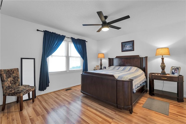 bedroom with light wood finished floors, baseboards, and a ceiling fan