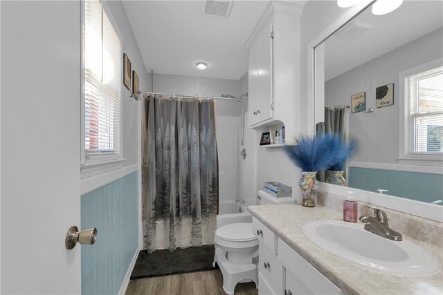 bathroom featuring vanity, wood finished floors, visible vents, shower / tub combo, and toilet