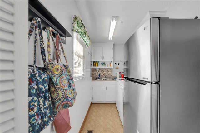 kitchen with light floors, light countertops, freestanding refrigerator, white cabinetry, and open shelves