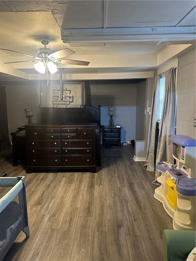 bedroom with concrete block wall and wood finished floors