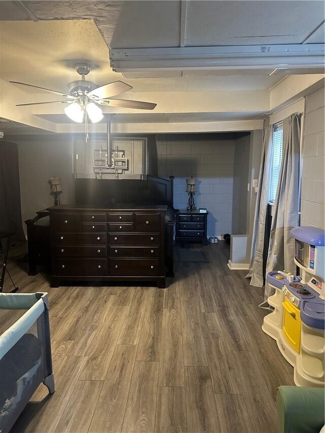 bedroom featuring concrete block wall and wood finished floors