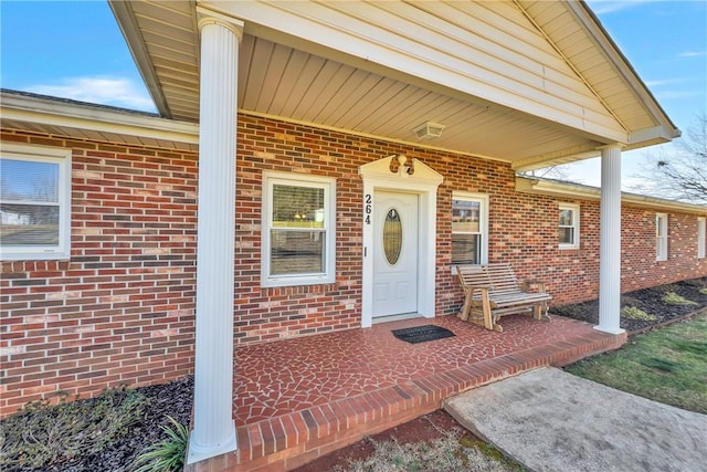 entrance to property featuring brick siding and a porch