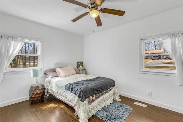 bedroom featuring visible vents, multiple windows, baseboards, and wood-type flooring