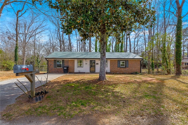 ranch-style house featuring brick siding, metal roof, a front yard, and fence