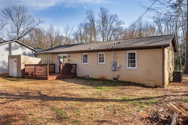 rear view of house featuring brick siding, a wooden deck, and central AC