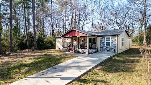 view of front of property featuring stone siding, covered porch, and a front yard