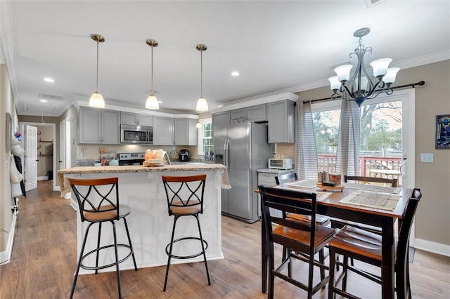 kitchen featuring light wood finished floors, gray cabinetry, stainless steel appliances, and crown molding