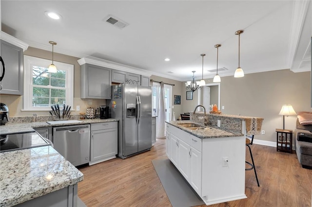 kitchen with light wood-type flooring, a sink, a kitchen breakfast bar, stainless steel appliances, and crown molding