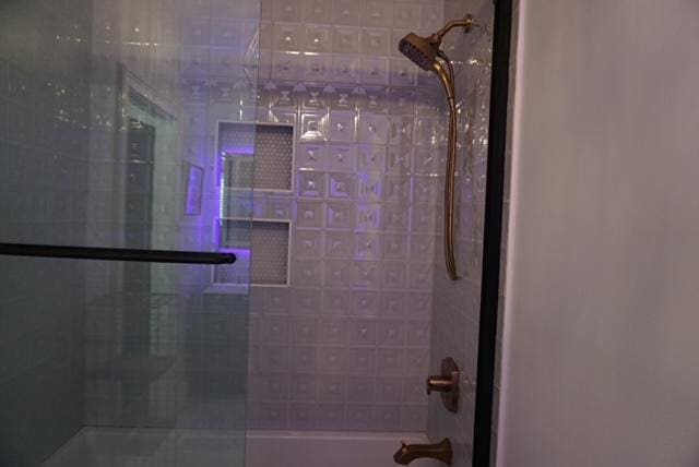 interior details featuring shower / bath combination with glass door