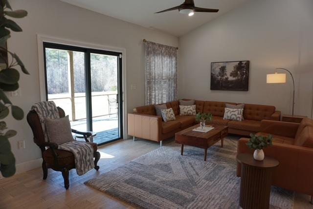 living area with baseboards, wood finished floors, ceiling fan, and vaulted ceiling