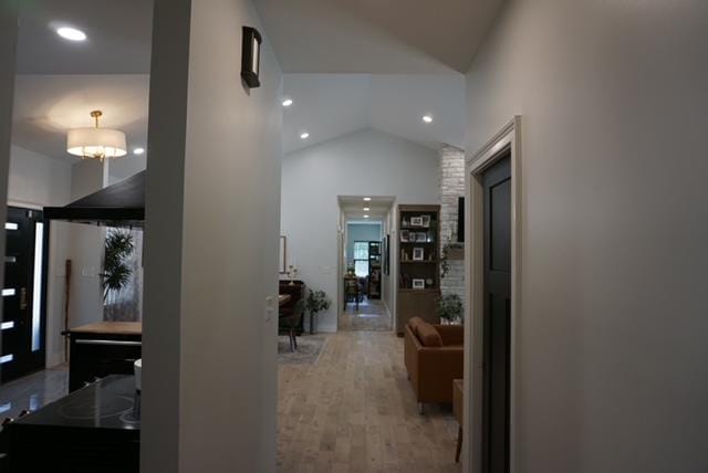 corridor featuring an inviting chandelier, vaulted ceiling, recessed lighting, and wood finished floors