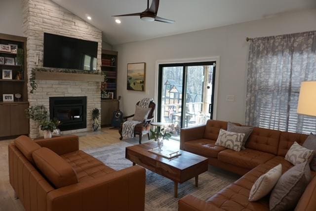 living area with ceiling fan, vaulted ceiling, a stone fireplace, recessed lighting, and wood finished floors