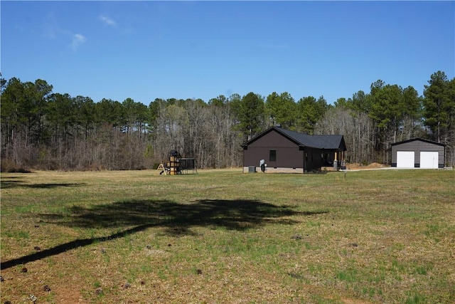 view of yard with an outbuilding, a forest view, and a detached garage