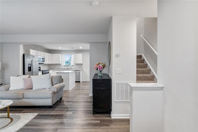 living area with visible vents, dark wood-style flooring, recessed lighting, baseboards, and stairs