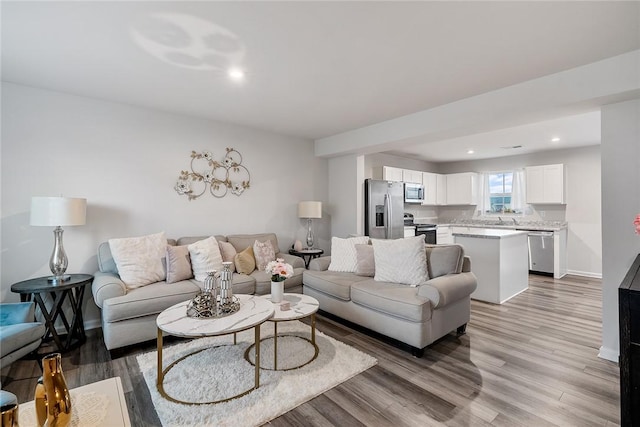 living area featuring recessed lighting, light wood-style flooring, and baseboards