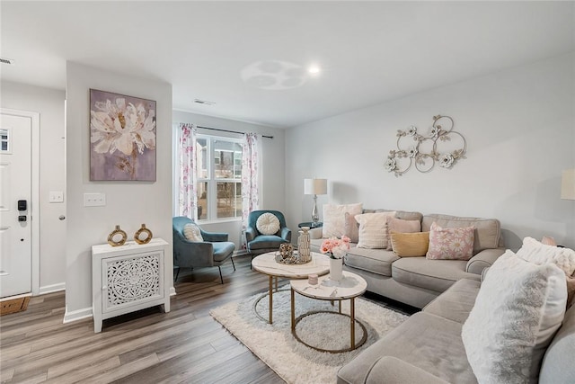 living area featuring light wood-type flooring, baseboards, and visible vents