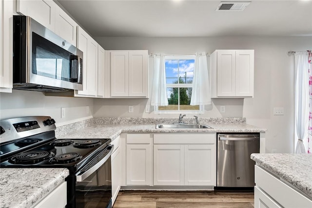 kitchen with a sink, stainless steel appliances, visible vents, and white cabinetry