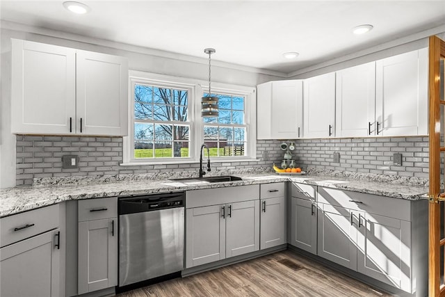 kitchen with light wood finished floors, gray cabinets, a sink, stainless steel dishwasher, and backsplash