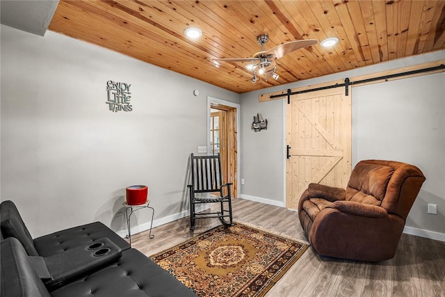 living area featuring wood finished floors, a barn door, wooden ceiling, baseboards, and ceiling fan