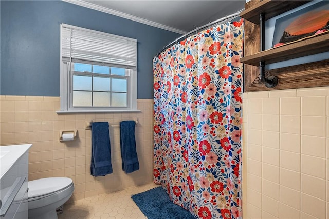 bathroom featuring a wainscoted wall, toilet, ornamental molding, tile walls, and tile patterned flooring