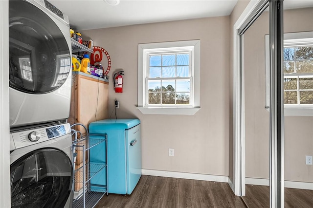 laundry room with stacked washer and dryer, a healthy amount of sunlight, wood finished floors, and laundry area