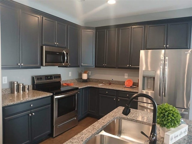 kitchen featuring appliances with stainless steel finishes, light stone countertops, and a sink