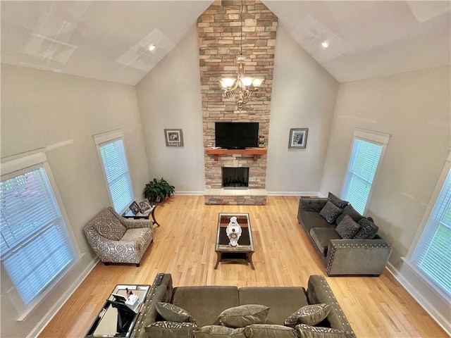 living area featuring baseboards, a chandelier, a fireplace, wood finished floors, and high vaulted ceiling