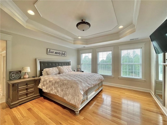 bedroom with light wood-type flooring, a raised ceiling, multiple windows, and visible vents