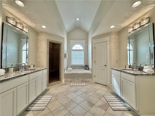 bathroom featuring a sink, a garden tub, lofted ceiling, and two vanities