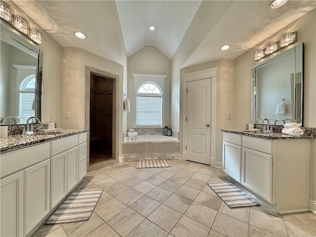 bathroom with a sink, lofted ceiling, a garden tub, and two vanities