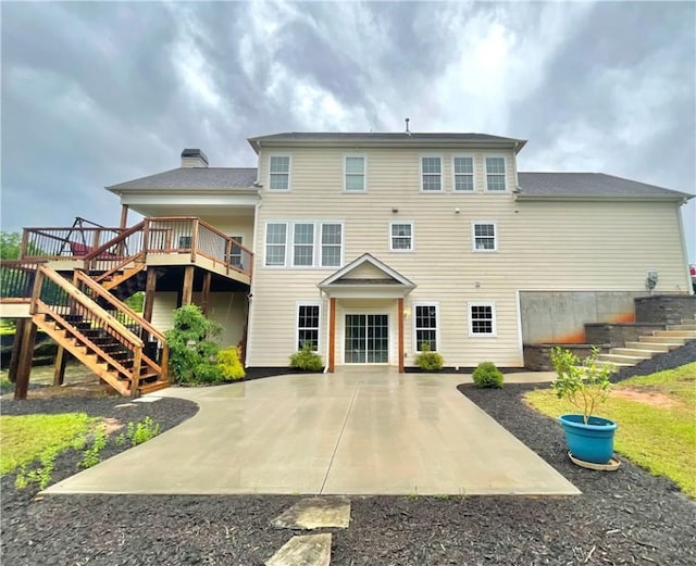 back of house with stairway, a patio area, and a chimney