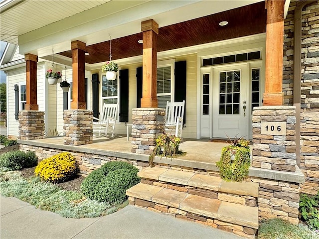 view of exterior entry with a porch and stone siding