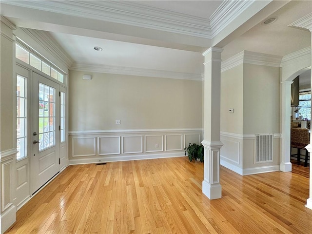 foyer featuring visible vents, light wood-style flooring, crown molding, and ornate columns