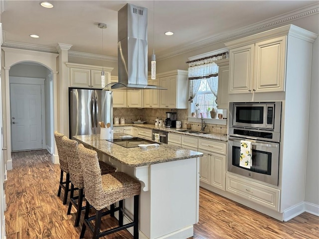 kitchen featuring ornamental molding, a sink, arched walkways, appliances with stainless steel finishes, and island range hood