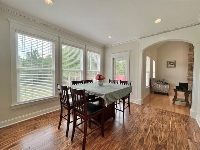 dining space featuring crown molding, baseboards, recessed lighting, wood finished floors, and arched walkways