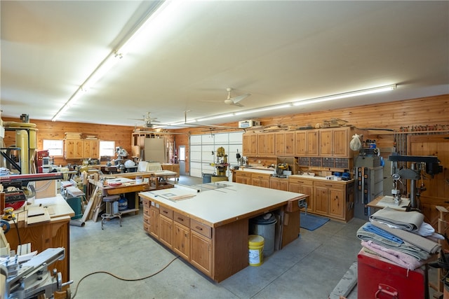 interior space with a workshop area, wood walls, and ceiling fan