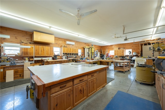 kitchen featuring a kitchen island, concrete floors, wood walls, a wall mounted air conditioner, and a ceiling fan