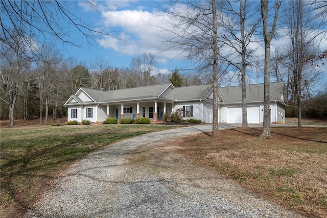 view of front of house with gravel driveway, a porch, a garage, and a front yard