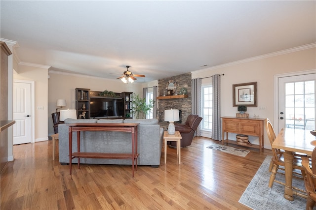 living area featuring light wood-style flooring, baseboards, crown molding, and ceiling fan